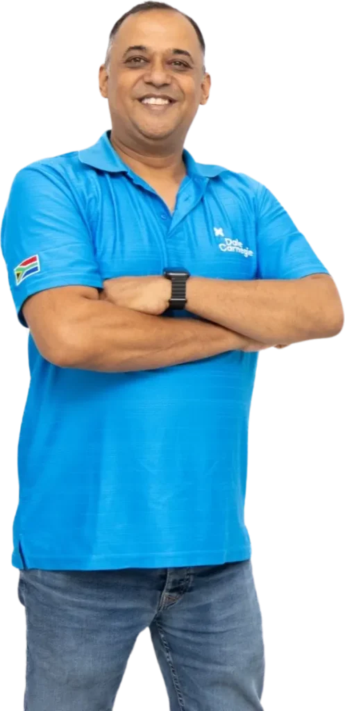 A Dale Carnegie trainer in a blue branded polo shirt, arms folded